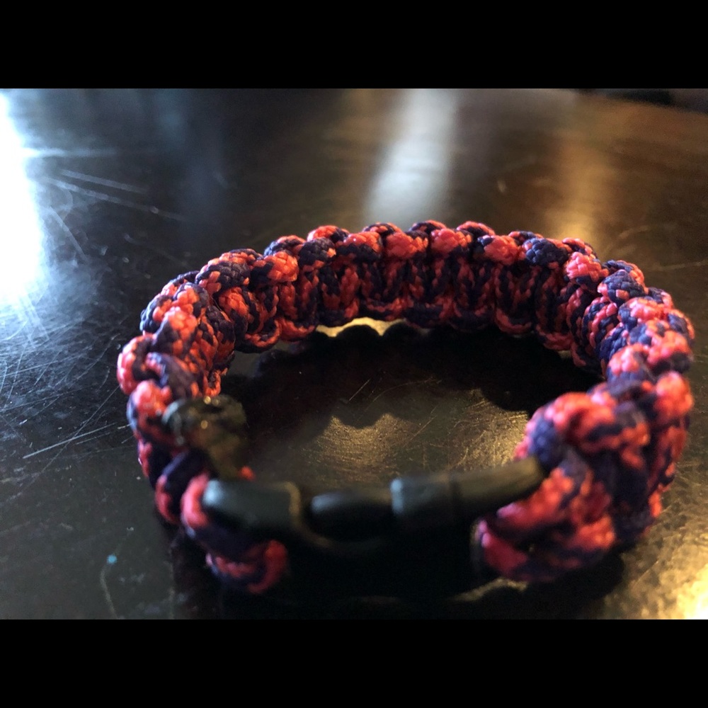 A pink and purple paracord bracelet w a black clip